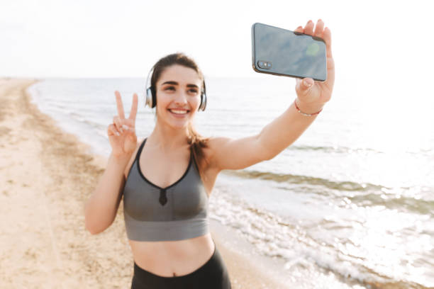 istock Smiling young sportswoman standing at the beach 1323998436