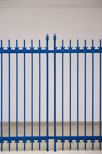 Closed blue metal gate near white wall. High quality photo