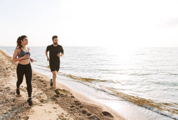 istock Sporty young couple jogging together on a beach 1323998829