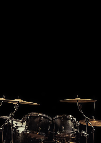 Parts of a drum kit in a dark room with a lot of space for additional text in frame