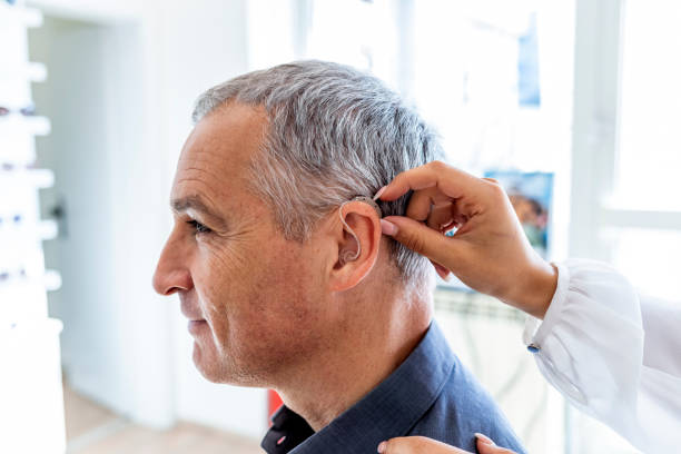 Nurse and patient with hearing aid Photo of female Doctor inserting hearing aid in man's ear hearing loss photos stock pictures, royalty-free photos & images