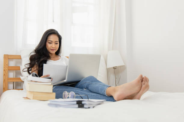 An Asian woman Education online from home She uses the headset via a laptop computer using a webcam. She avoids an outbreak of the coronavirus. The internet is everything.