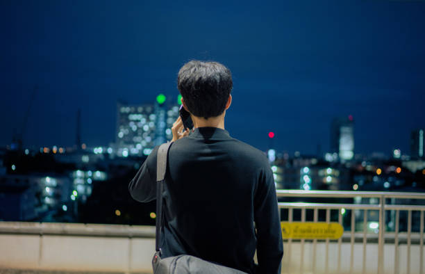 asian business man using phone while waiting at train station