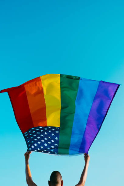 istock young man waving a rainbow US flag on the sky 1324002430