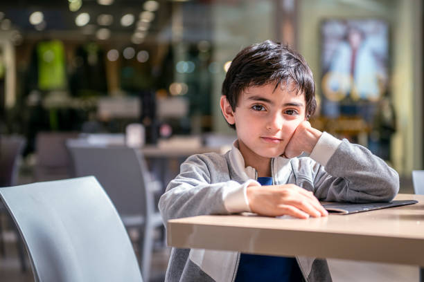 istock bored kid waits at a restaurant table in a shopping mall 1324004554