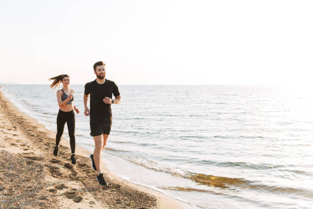 istock Sporty young couple jogging together on a beach 1324004801