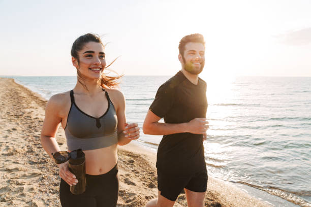 istock Happy young couple jogging together on a beach 1324005952