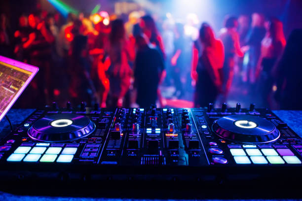 music controller DJ mixer in a nightclub at a party music controller DJ mixer in a nightclub at a party against the background of blurred silhouettes of dancing people sound mixer photos stock pictures, royalty-free photos & images