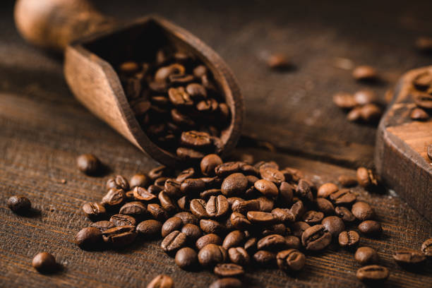 coffee beans with wooden scoop - kavrulmuş kahve çekirdekleri stok fotoğraflar ve resimler
