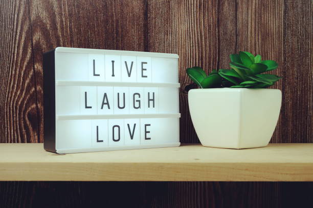 Live Laugh Love word in light box on wooden background