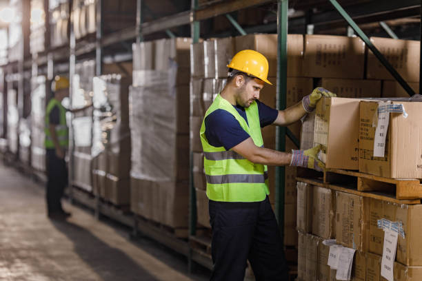 istock Young warehouse worker working cardboard boxes in industrial building. 1324008965