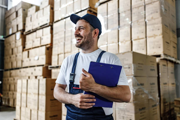 happy worker with a checklist in distribution warehouse. - warehouse worker imagens e fotografias de stock