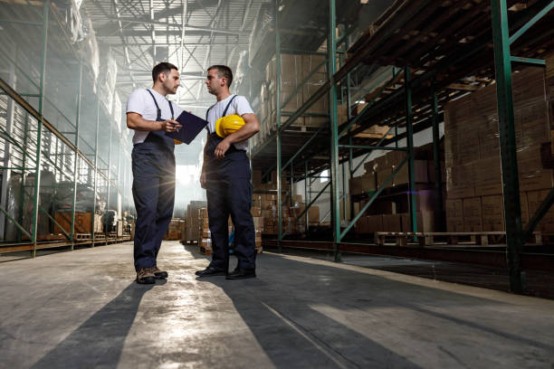 istock Young manual workers talking about a checklist at distribution warehouse. 1324009150