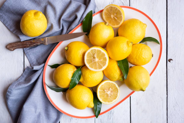 istock Fresh and ripe lemons with leaves on white wooden table 1324009332