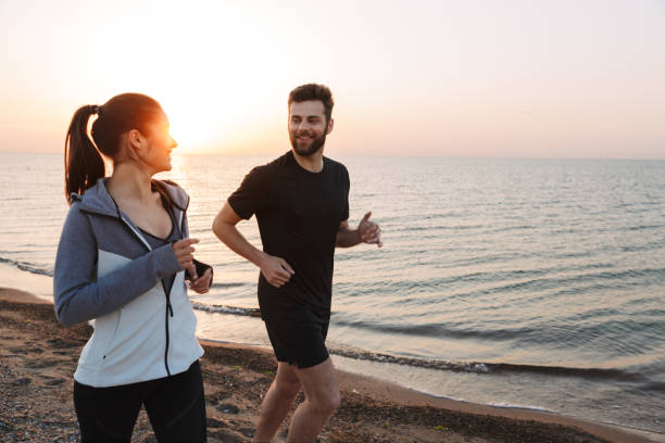 istock Happy young couple jogging together on a beach 1324009491