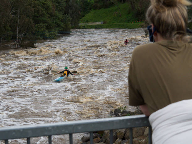 Whitewater Kayakers in flooded Yarra River Dights Falls weir after wild storms Victoria has experienced severe storms and heavy rain causing flooding and damage in early June 2021. Photo of people in kayaks taking advantage of the Yarra River flooding from Dights Falls weir in Abbotsford on 13 June, showing whitewater rapids and floodwaters. yarra river stock pictures, royalty-free photos & images