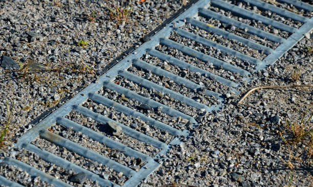 istock Drainage of the path by means of a gutter under which water flows. the gutter is covered with a metal grid. grassy area with paths on the slope 1324011575