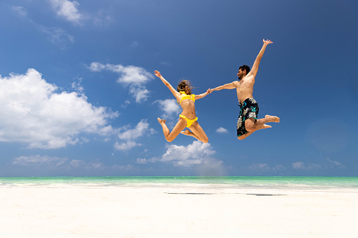 Young businesswoman jumping of joy on the beach.