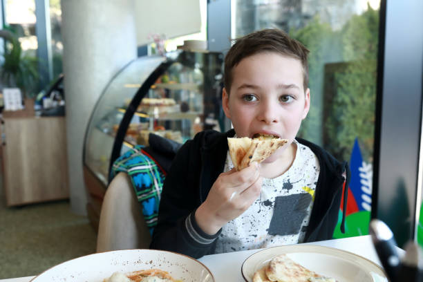 istock Boy eating piece of four cheese pizza 1324014263