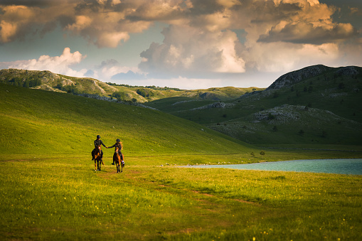 Tourist couple enjoying horseback riding by the lake and holding hands