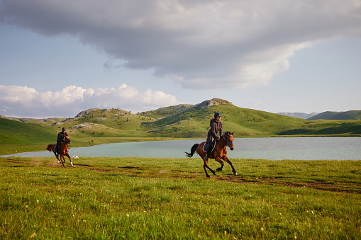 Tourist couple enjoying horseback riding by the lake