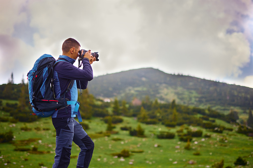 Young man taking photographs while hiking in the mountains