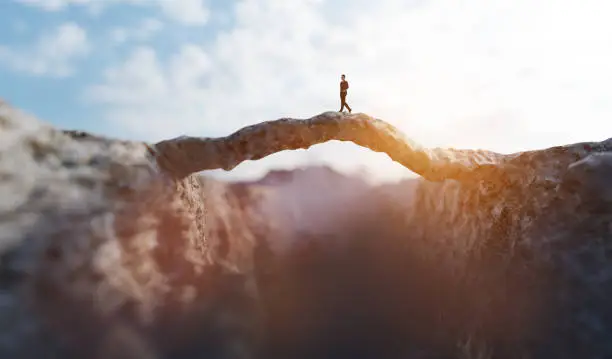 Photo of Man walking on the other side of mountain bridge.