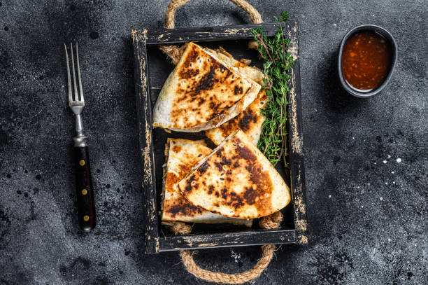 istock Mexican quesadilla with chicken, tomato, corn and cheese. Black background. Top view 1324021934