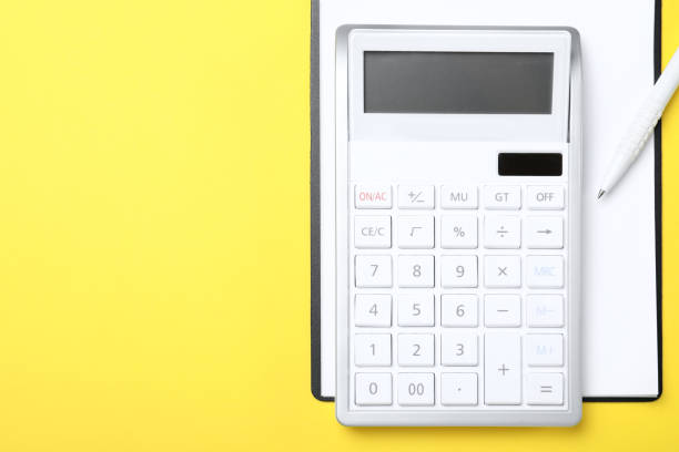 istock Calculator, clipboard and pen on yellow background, top view. Space for text 1324022117