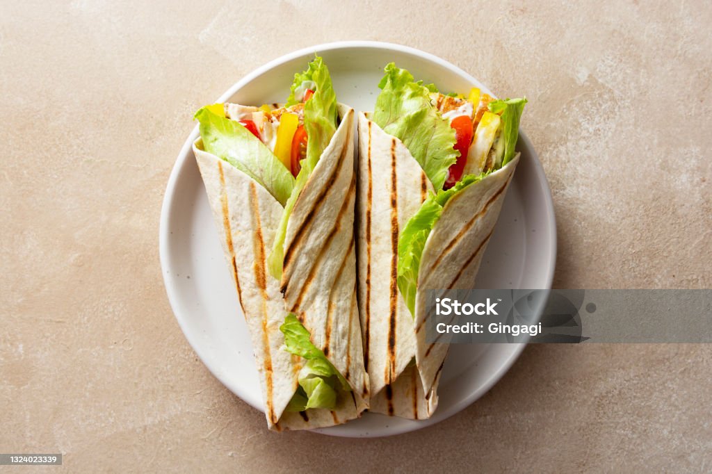 Wrap burrito sandwich or kebab with flatbread with vegetables and white meat. Delicious healthy food, take away snack Wrap burrito sandwich or kebab with flatbread with vegetables and white meat. Delicious healthy food, take away snacks Wrap Sandwich Stock Photo