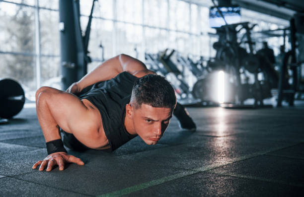 istock Strong young man in sportive clothes doing push ups in gym 1324025355