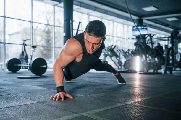 istock Strong young man in sportive clothes doing push ups in gym 1324025358