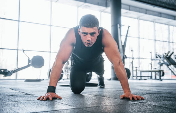 istock Strong young man in sportive clothes doing push ups in gym 1324025668