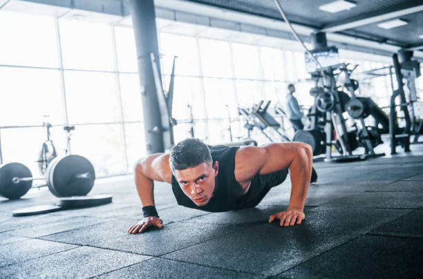 istock Strong young man in sportive clothes doing push ups in gym 1324026556