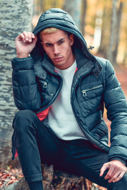 istock Modern Male In Warm Jacket Sitting On Tree Stump In Forest 1324026943