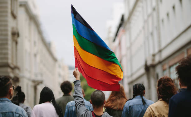 People in a gay pride parade Rear view of people in the pride parade. Group of people on the city street with gay rainbow flag. Pride stock pictures, royalty-free photos & images