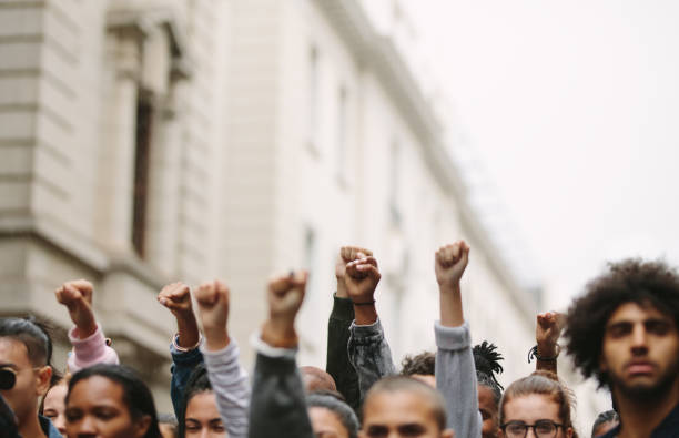 armas levantadas en señal de protesta - fist fotografías e imágenes de stock