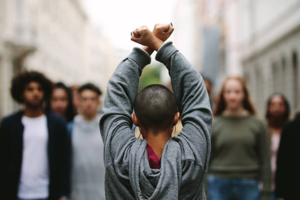Young man leading a protest march. Riot on the streets of a city. Rebellion, protest, riot, student march, rebellious youth, anti-government and anti-dictatorship concepts.