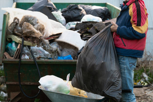 istock Young man throws out a large plastic garbage bag to the garbage container outdoors 1324028164