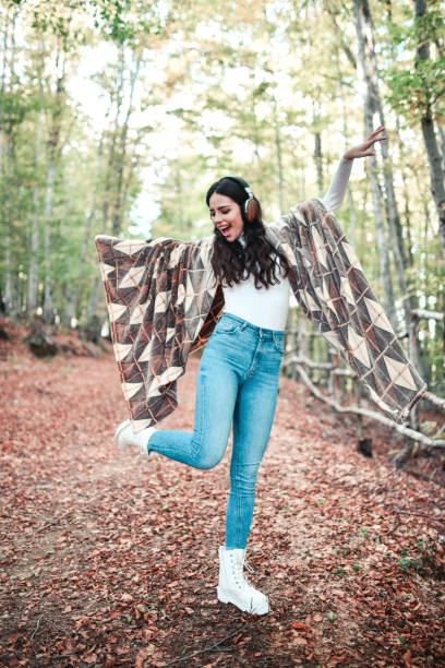 istock Happy Female Dancing In Forest To Music While Warming With Blanket 1324029851