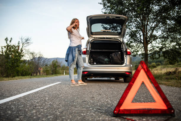 The woman calls the roadside assistance service. One woman is standing alone on the road next to her car and calling the roadside assistance service. vehicle breakdown stock pictures, royalty-free photos & images