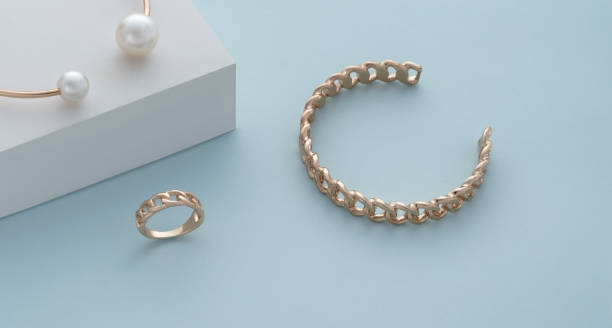 istock Chain shape golden bracelet and ring on blue background 1324031782