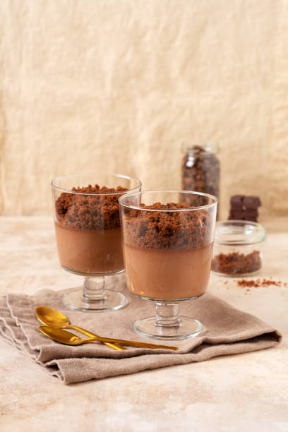istock Chocolate mousse with brownie in glass jars on a light slate, stone or concrete background. Delicious dessert. Selective focus 1324033095