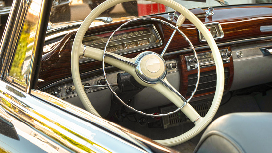 Front seat and steering wheel of a classic car viewed from outside the window looking in