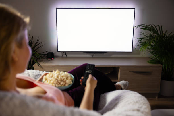 istock Woman watching TV at home, empty white TV screen mockup 1324038767
