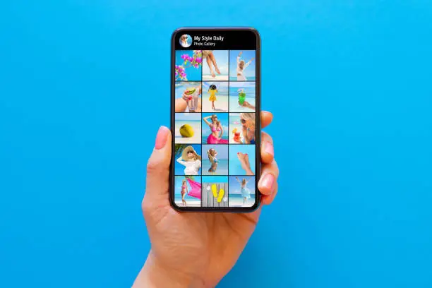 Photo of Someone's photo gallery on social media shown on the screen of mobile phone on blue background