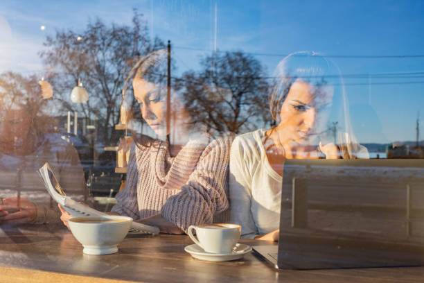 istock View through window of female friends studying in coffee bar 1324040607