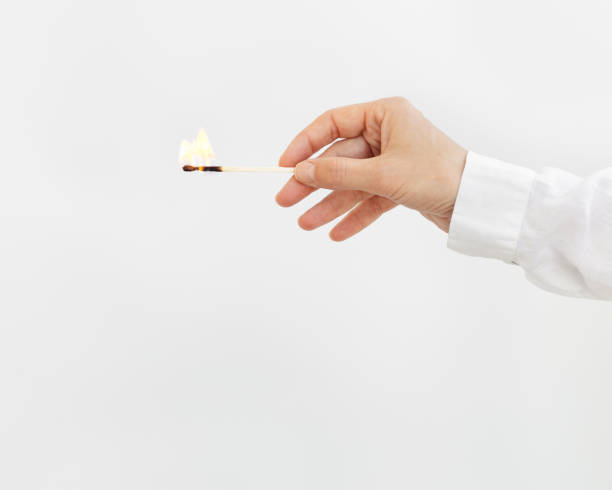 female hand holds lit match. wooden matchstick with fire. fire hazard concept. - fire match women flame imagens e fotografias de stock