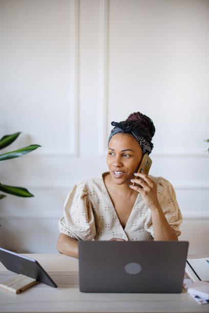 istock Businesswoman talking on phone while using laptop 1324041088