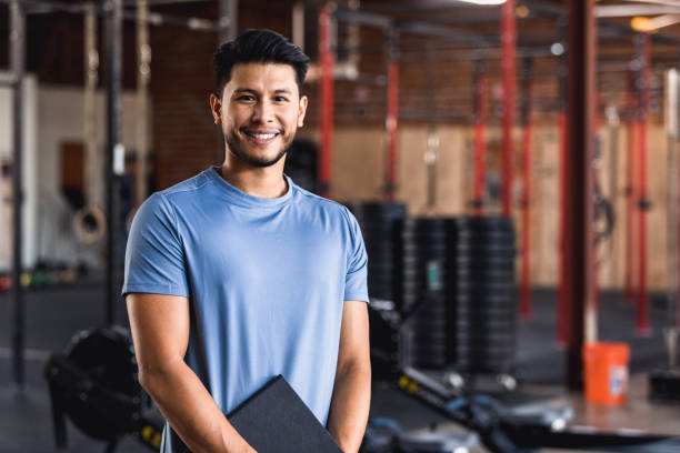 Confident gym owner The owner of a cross training gym smiles confidently at the camera. fitness instructor stock pictures, royalty-free photos & images